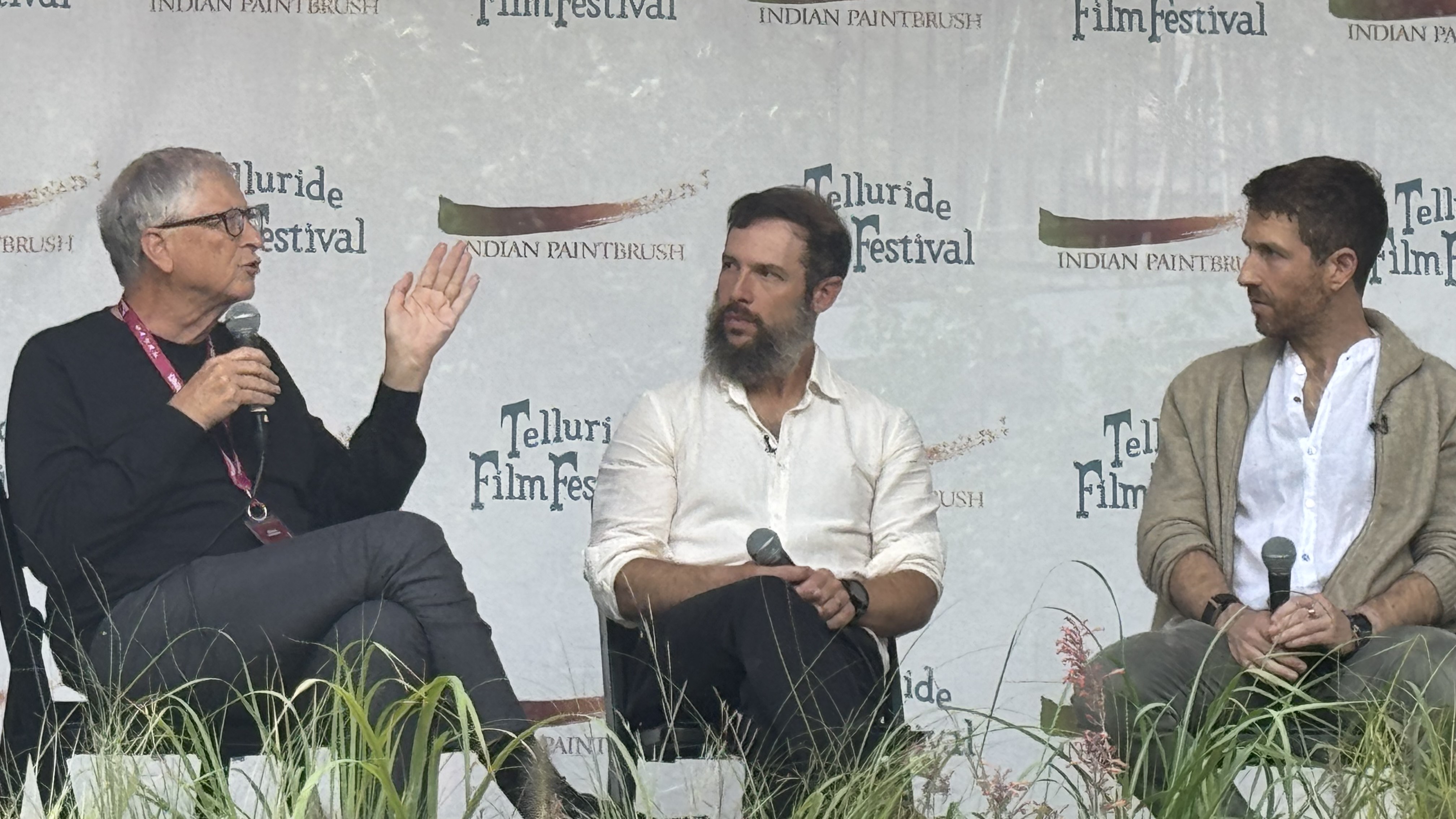 Bill Gates habla con micrófono durante un panel sobre IA junto a Aza Raskin y Tristan Harris en Telluride.